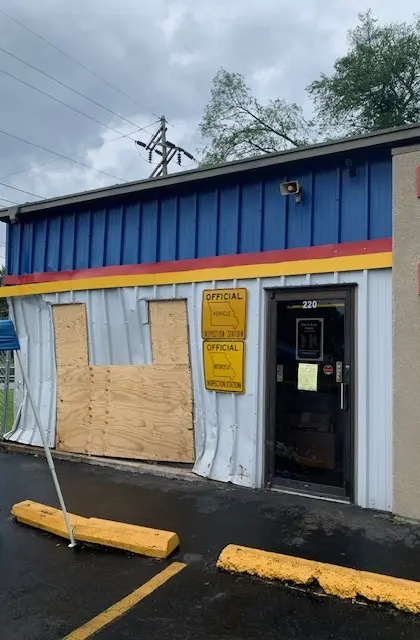 Storefront with boarded window and parking lot.