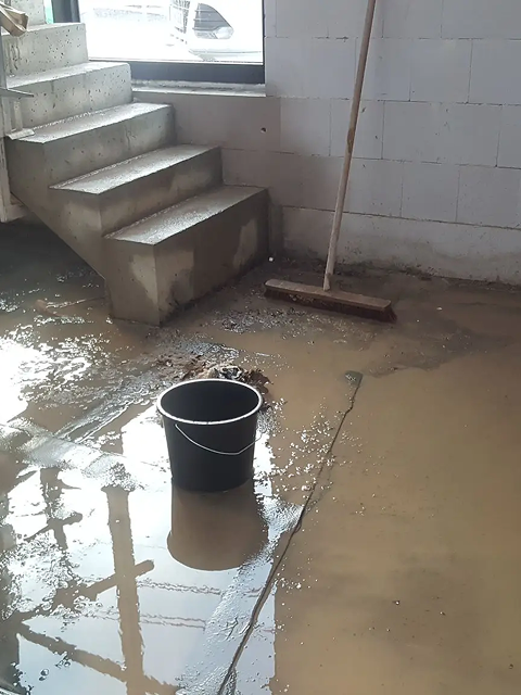Wet concrete floor with bucket and broom.