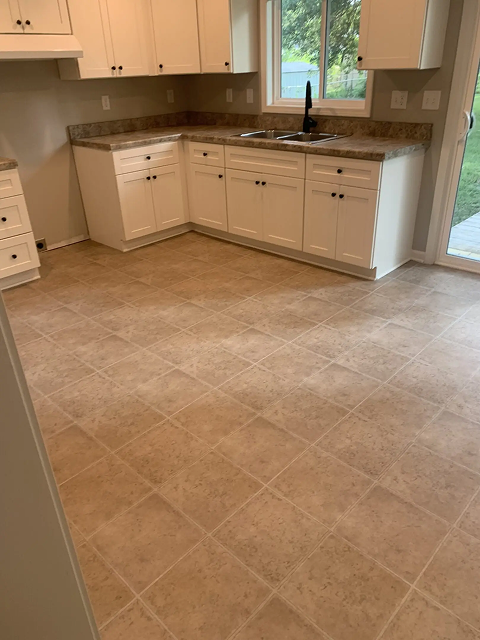 Spacious kitchen with tiled floor and cabinets.