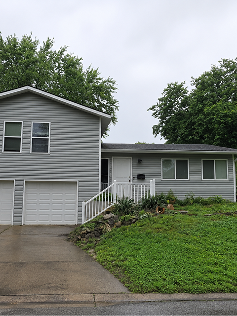 Gray house with two-car garage and lawn.