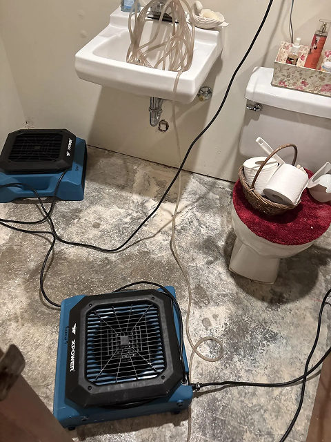 Bathroom with fans drying wet floor.