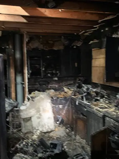 Fire-damaged kitchen with debris and destruction.