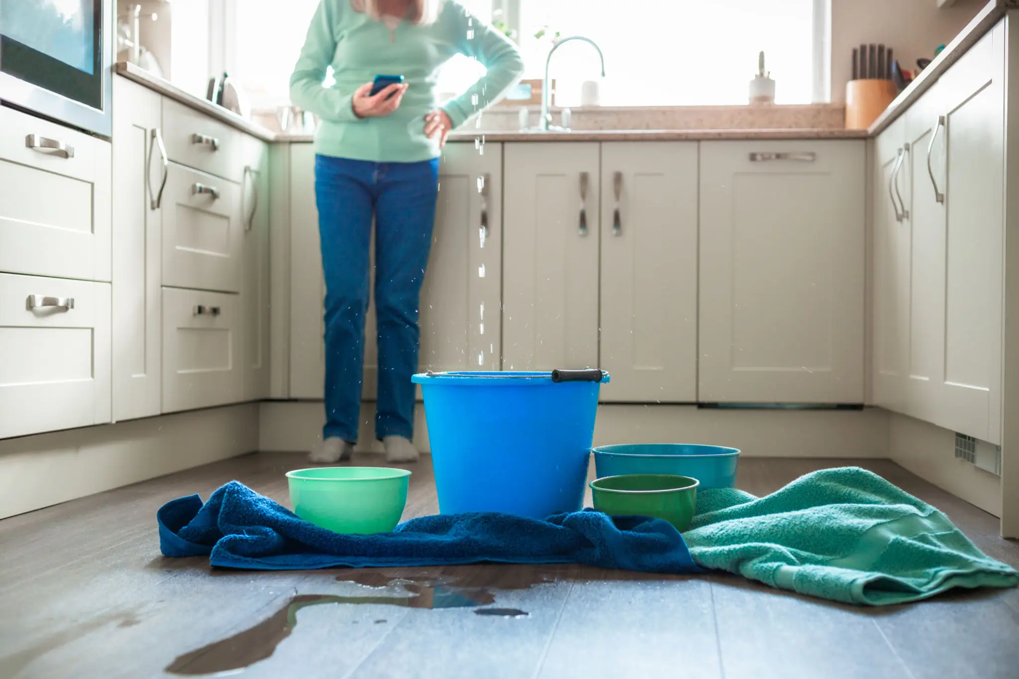 Kitchen leak with buckets and towels.