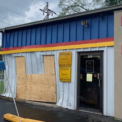 Building with boarded window and yellow sign.